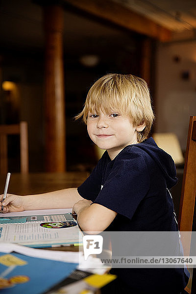 Seitenansicht Porträt eines süßen Jungen  der am Tisch lernt