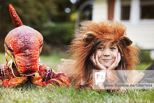 Kinder in Kostümen  die an Halloween im Gras liegen