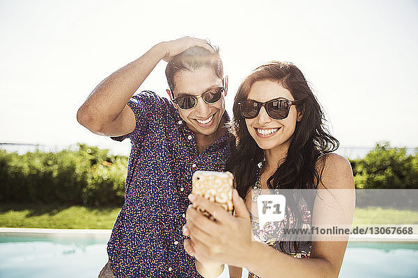 Glückliches Paar  das Selfie nimmt  während es gegen den klaren Himmel steht