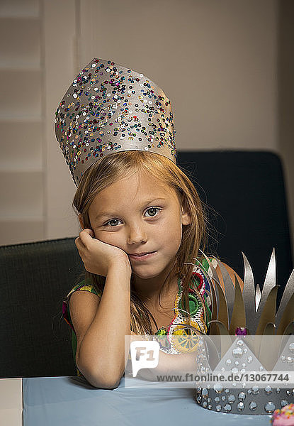 Porträt eines Mädchens mit Krone bei Tisch zu Hause sitzend