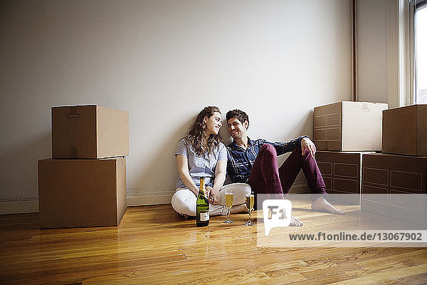 Couple with wineglasses sitting on floor at home