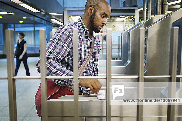 Mann durchzieht Chipkarte am Bahneingang
