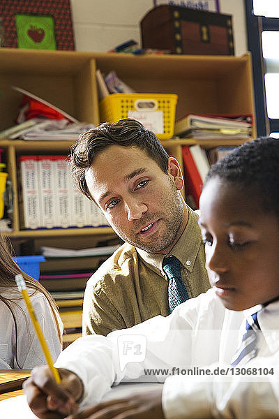 Teacher looking at student during lesson in classroom