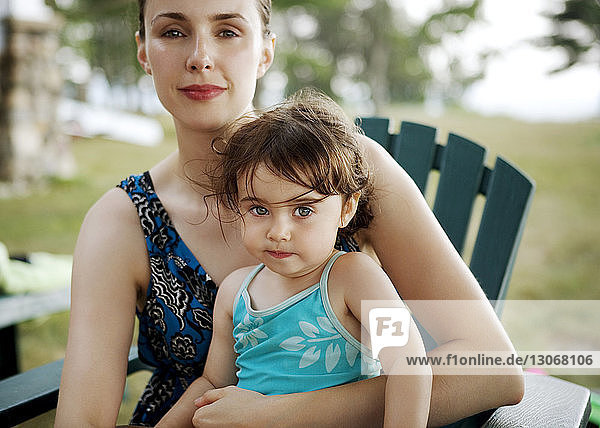 Portrait of mother and daughter sitting on chair