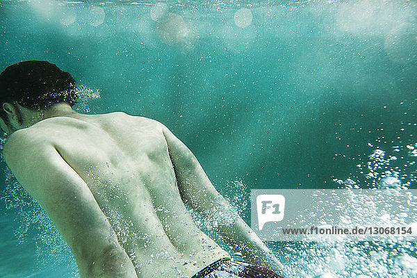 Rückansicht eines unter Wasser schwimmenden Menschen