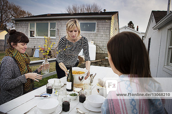 Frau serviert im Winter Essen für Freunde bei Tisch auf der Veranda