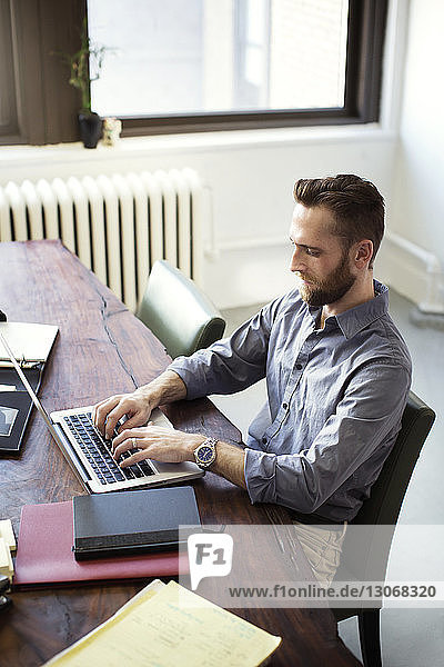 Hochwinkelansicht eines Geschäftsmannes mit Laptop-Computer  während er im Büro sitzt
