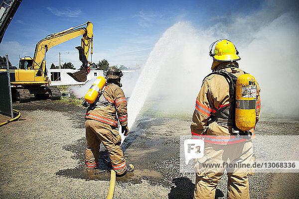 Feuerwehrleute  die an sonnigen Tagen Wasser versprühen  um Brände zu stoppen