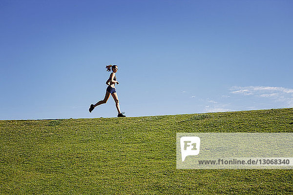 Frau rennt auf Grasfeld gegen klaren Himmel