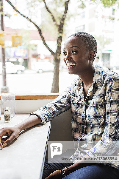 Lächelnde Frau schaut weg  während sie im Restaurant sitzt