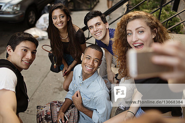 High angle view of woman taking selfie with friends while sitting on steps