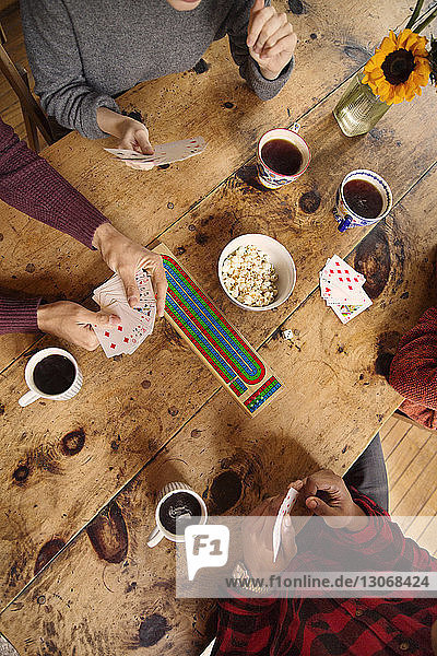 High angle view of friends playing cards while having coffee at home