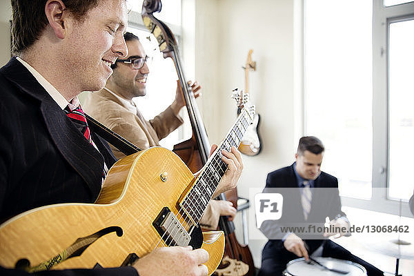 Smiling men practicing in music studio