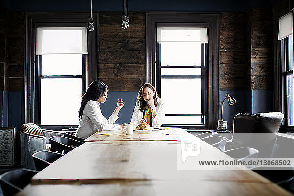 Geschäftsfrauen diskutieren  während sie im Büro am Schreibtisch sitzen