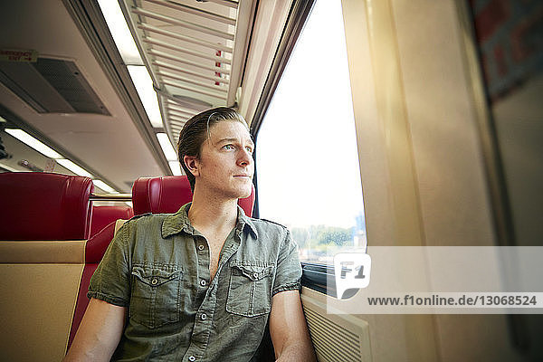 Mann schaut durch ein Fenster  während er im Zug reist