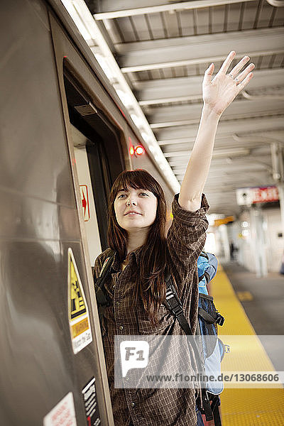 Frau winkt mit der Hand  während sie sich aus dem Zug lehnt