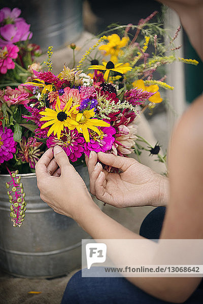 Ausgeschnittenes Bild einer Frau  die Blumen in einem Topf zum Verkauf im Geschäft berührt