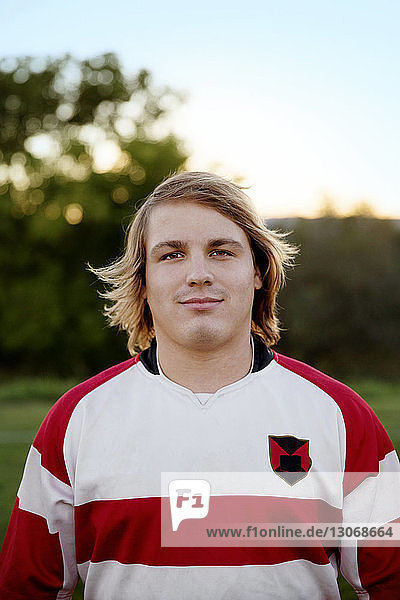 Selbstbewusster Rugby-Spieler steht auf dem Feld gegen den Himmel