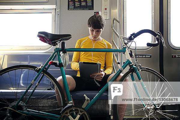 Seitenansicht eines Mannes mit Fahrrad  der am Bahnsteig auf den Zug wartet