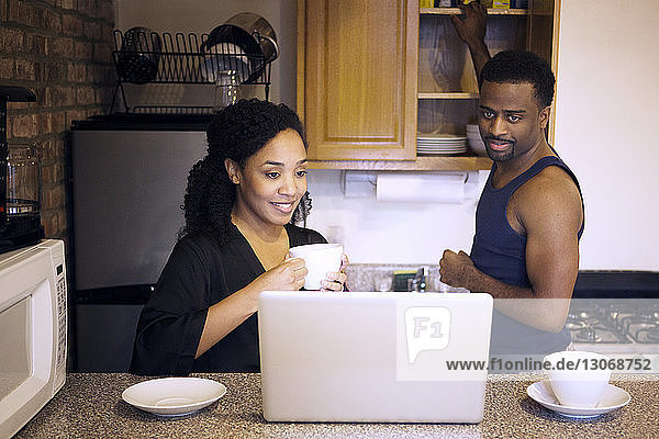 Couple looking at laptop computer while standing in kitchen