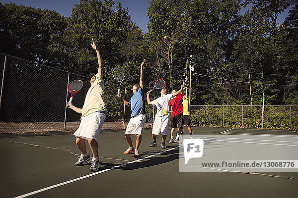 In der Reihe stehende Spieler spielen Tennis auf dem Platz
