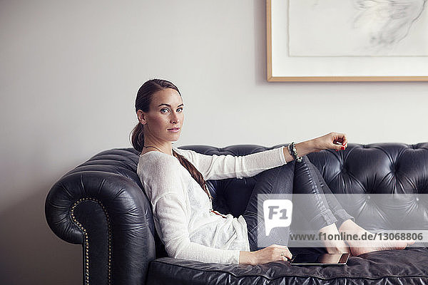 Porträt einer Frau  die zu Hause auf dem Sofa sitzt