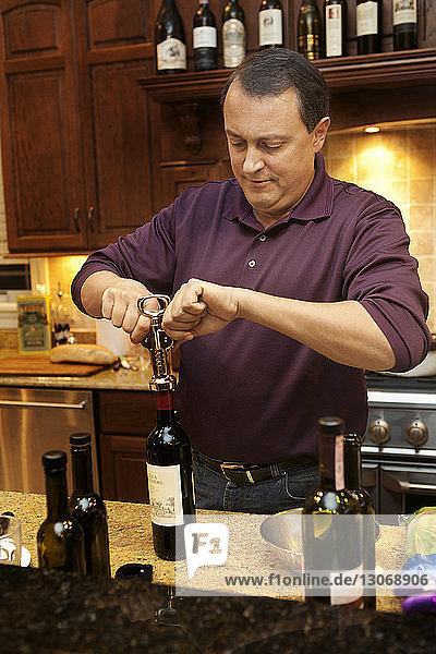 Mann öffnet Wein in Küche