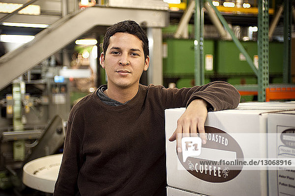 Porträt eines an einen Karton gelehnten Mannes in der Kaffeeindustrie