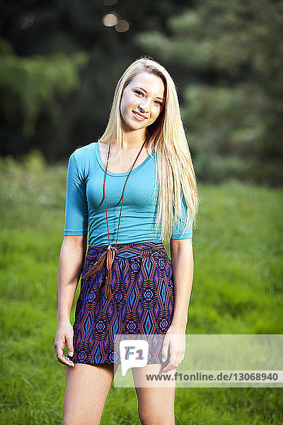Porträt eines lächelnden Teenager-Mädchens auf Grasfeld stehend