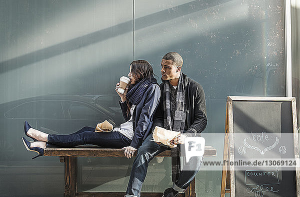 Paar  das auf einer Bank vor einem Café sitzt