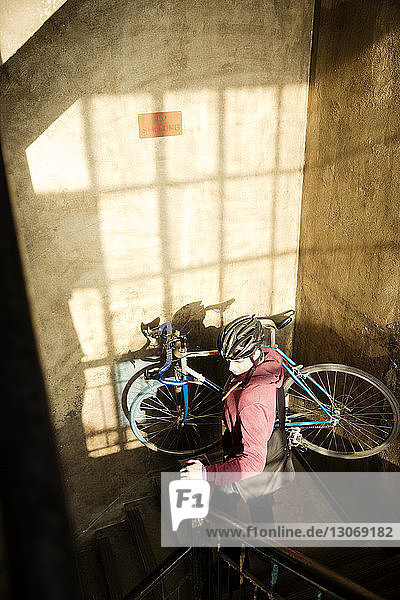 High angle view of man carrying bicycle down staircase