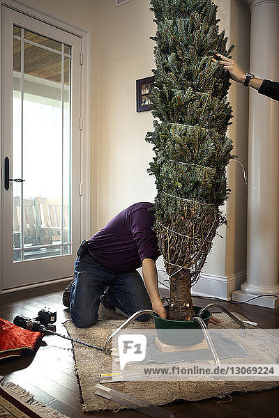 Mann schmückt Weihnachtsbaum zu Hause