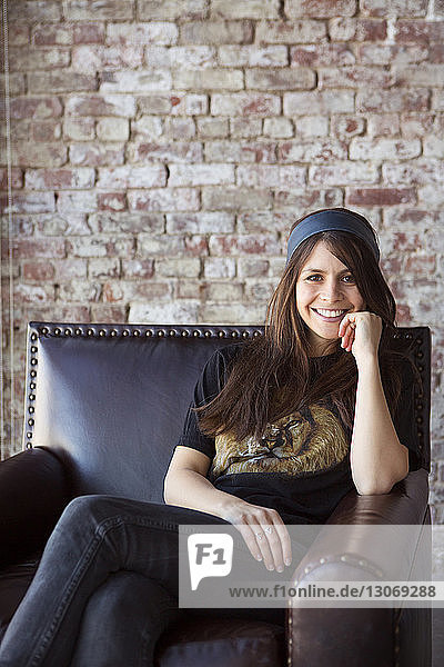 Porträt einer fröhlichen Frau  die zu Hause auf einem Sessel sitzt