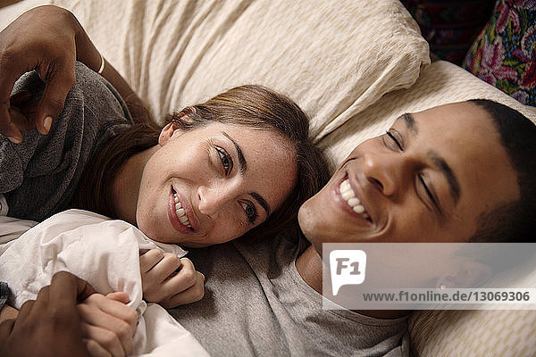 Smiling couple lying on bed at home