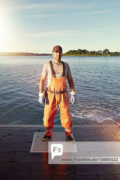 Portrait of confident fisherman standing on pier