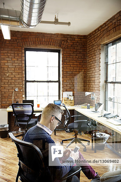 Geschäftsmann benutzt ein Smartphone  während er im Büro sitzt