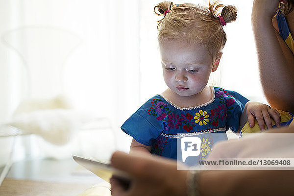 Kleines Mädchen betrachtet Tablet-Computer mit der Mutter zu Hause