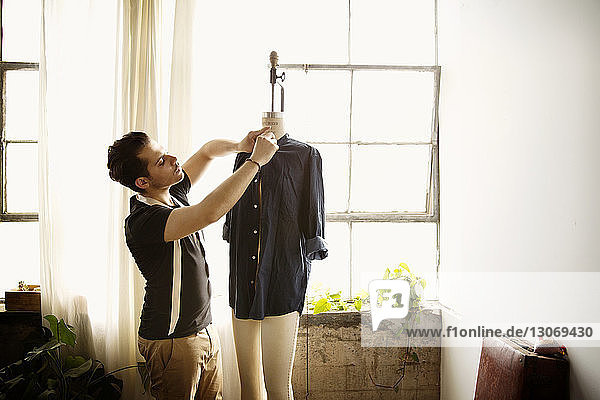 Modedesignerin prüft Hemd auf Schneiderinnenmodell während der Arbeit in der Werkstatt