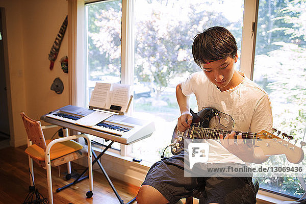Teenager practicing electric guitar at home
