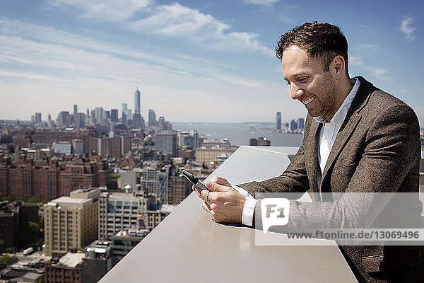 Happy businessman using tablet computer on building terrace