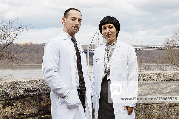 Portrait of doctors standing by retaining wall against bridge