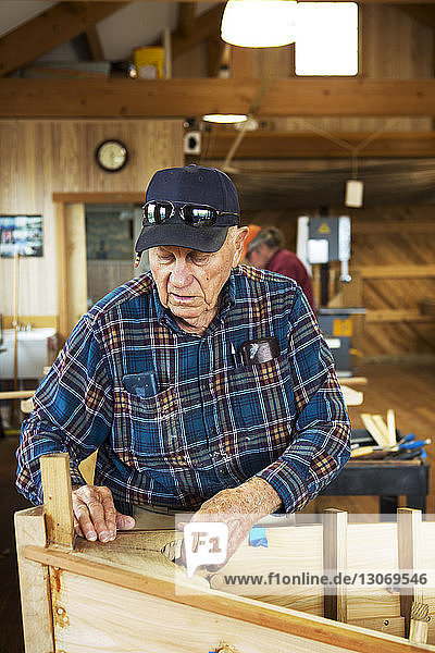 Älterer Mann arbeitet am Kanu in der Werkstatt