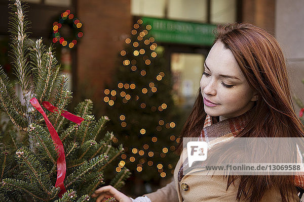 Frau kauft im Geschäft den Weihnachtsbaum ein