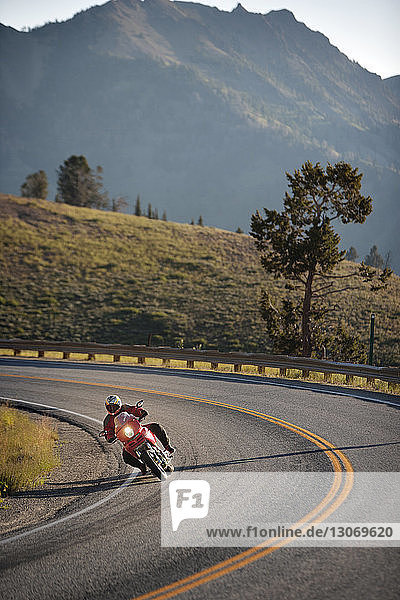 Mann fährt Motorrad auf Straße gegen Berg