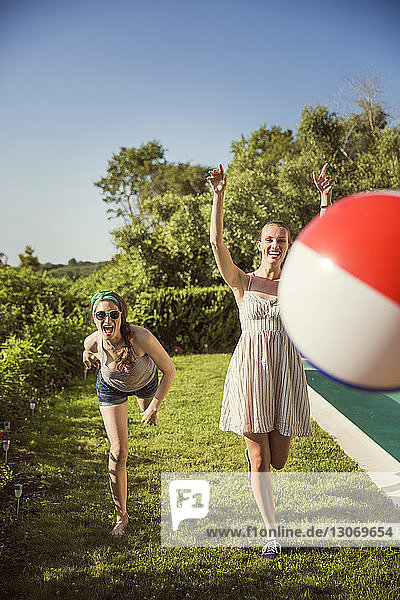 Fröhliche Freunde spielen an einem sonnigen Tag mit dem Ball im Hinterhof