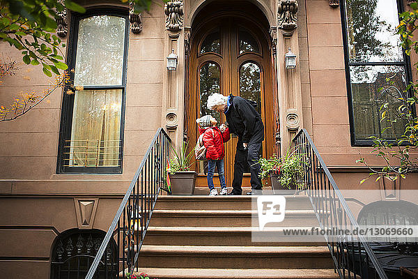 Großmutter mit Mädchen auf Stufen gegen Haus stehend