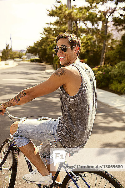 Side view of happy man riding bicycle on road