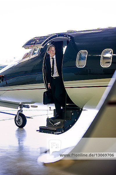 Geschäftsmann schaut weg  während er auf einer Flugzeugtreppe steht