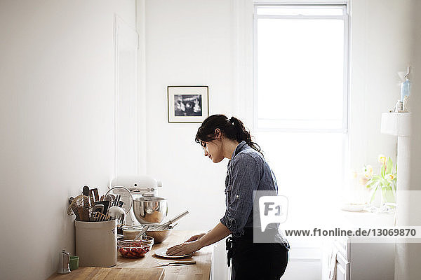 Seitenansicht einer Frau  die zu Hause Essen zubereitet
