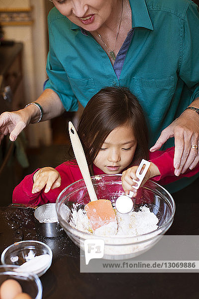 Frau hilft Enkelin bei der Zubereitung von Essen zu Hause